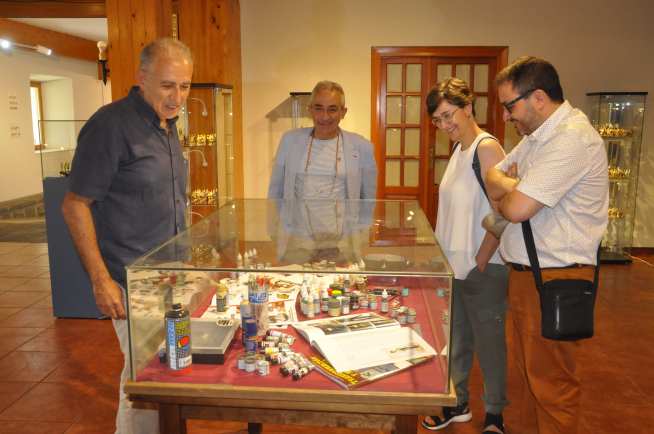 Diego Fernández, Julio Rina y dos de los donantes observan una vitrina con material para fabricar miniaturas.