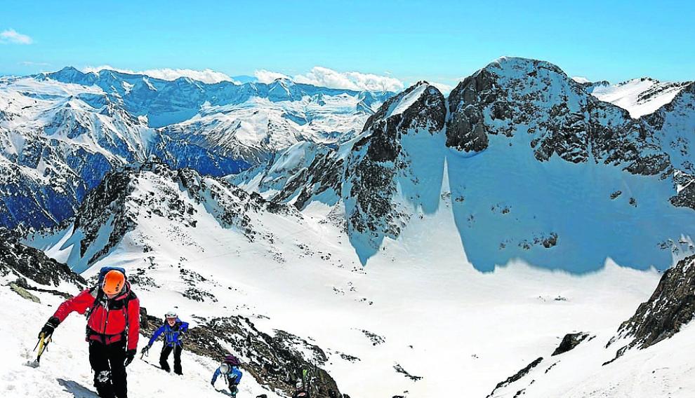 Los miembros del club de montaña ascienden las últimas pendientes antes de llegar a los picos de los Infiernos, con el Garmo Negro al fondo de la panorámica.
