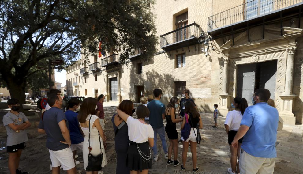 Grupo de turistas atendiendo a las explicaciones del guía en la plaza de la Catedral de Huesca.