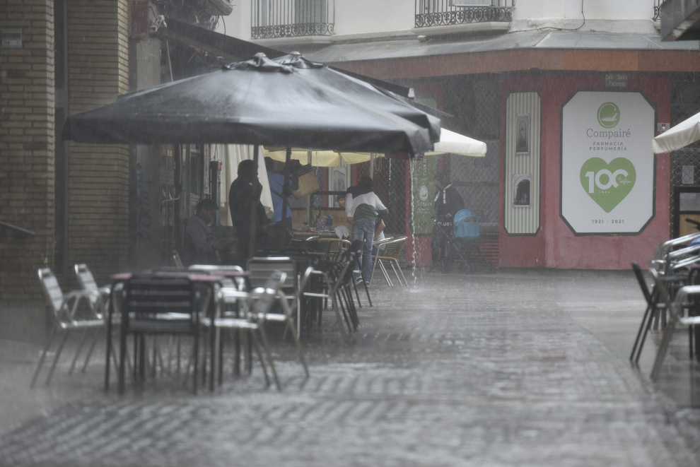 Varias personas se protege de la lluvia en una terraza en Huesca.