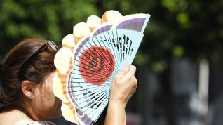 Una mujer se cubre la cara con un abanico