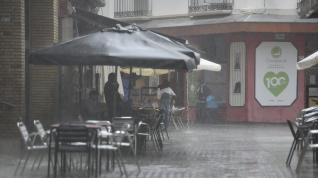 Varias personas se protege de la lluvia en una terraza en Huesca.