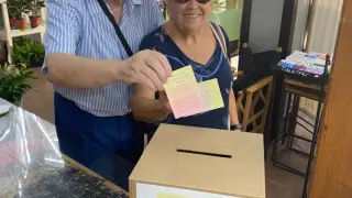 Dos usuarios echan papeletas selladas a la urna para el sorteo de El Monegrazo del verano.