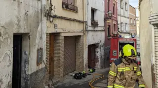 Bomberos junto a la vivienda de Monzón afectada por el incendio.