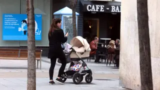 Una mujer pasea un carrito de bebé por la capital oscense.