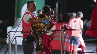 Miembros de la cruz roja atienden a uno de los niños que ha llegado junto a un grupo de unos 60 inmigrantes