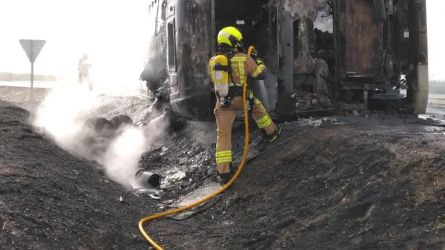 Bomberos en la extinción del camión incendiado en la carretera de Poleñino.