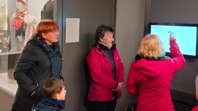 Elena Gusano presenta la nueva pantalla interactiva a un grupo de visitantes del museo.