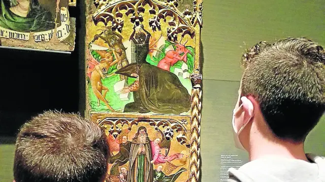 Dos niños miran el Retablo de San Antonio Abad de Monzón, expuesto en el Museo de Lérida.