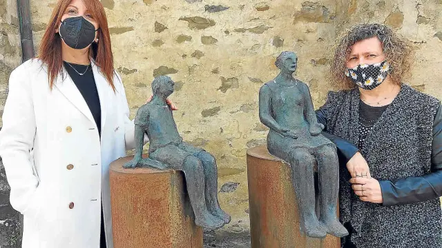 La alcaldesa de Sabiñánigo, Berta Fernández, y la concejala Marisa Morillo, junto a la escultura homenaje a la maestra rural.
