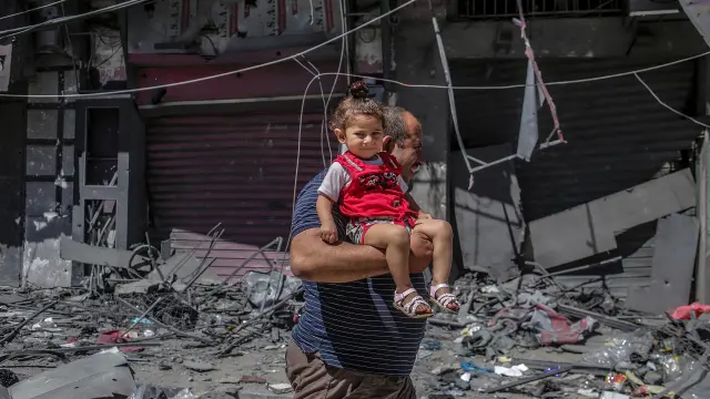 Un hombre palestino huye con su hija en brazos después del ataque ayer a una torre en la ciudad de Gaza.