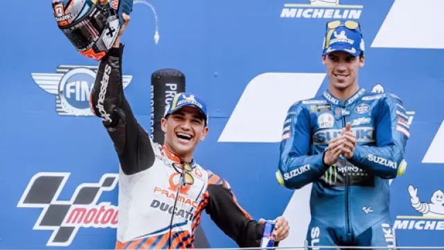 Jorge Martín celebra su primera victoria en MotoGP, con Joan Mir aplaundiéndole desde el podio.