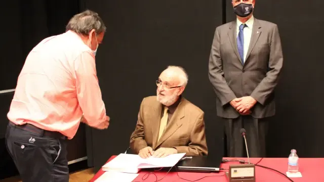 Isidro Bango Torviso (en el centro) firma un ejemplar de su libro, en el Palacio de Congresos de Jaca, en presencia de Juan Carlos Moreno, presidente de la Asociación Sancho Ramírez.