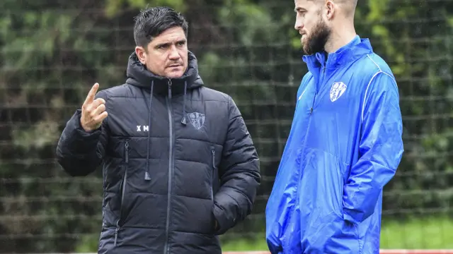 Joaquín cambia impresiones con Pulido, el sábado, durante el entrenamiento del Huesca en Mareo.