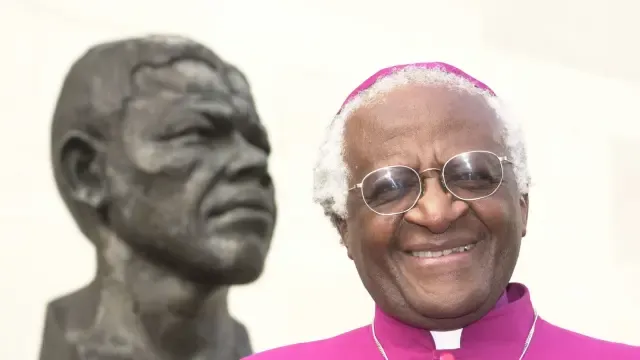 Imagen de Desmond Tutu ante un busto de Nelson Mandela con quien lideró la tarea de reconciliar a la nación tras la democracia.