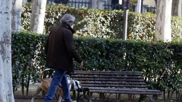 Un vecino de Huesca paseando por el Parque Miguel Servet con su perro.