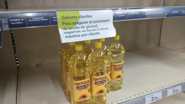 Un cartel, en un estante casi vacío, limita la compra de aceite de girasol en un supermercado.