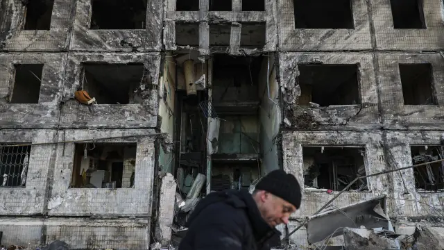 Un hombre trabaja en las tareas de limpieza de un edificio bombardeado.