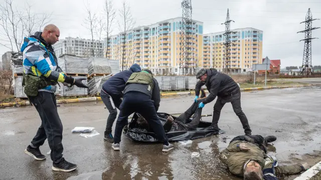 Personal civil retira uno de los muchos cuerpos hallados en las calles tras el abandono del ejército ruso en Bucha.