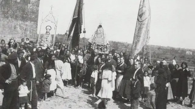 El pueblo de Sariñena, de todas las edades, asiste a la procesión del año 1934, con banderas y santos identificados en la imagen.