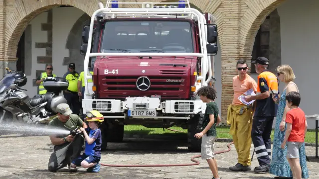 Un bombero enseña a un niño a usar una manguera.