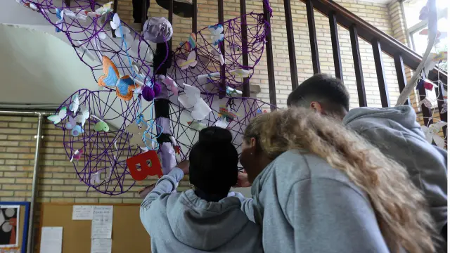 Alumnado del IES Lucas Mallada, junto a la estructura de mariposas creada con motivo del 25N.