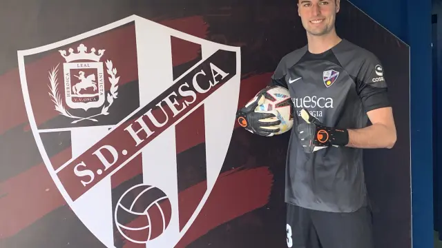 Juan Pérez posa junto al escudo de la SD Huesca en su presentación.
