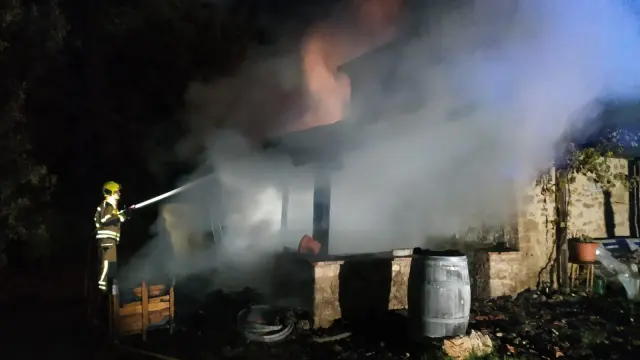 Los bomberos extinguen el incendio producido en la casa del anciano.