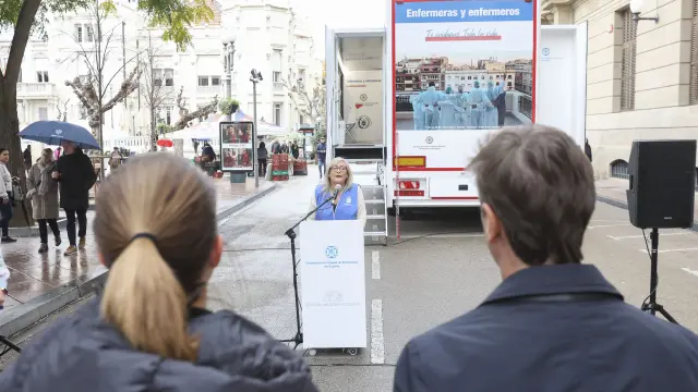 La presidenta delColegio oscense, CarmenTosat, ante el camión de la Ruta Enfermera, durante la apertura del acto.