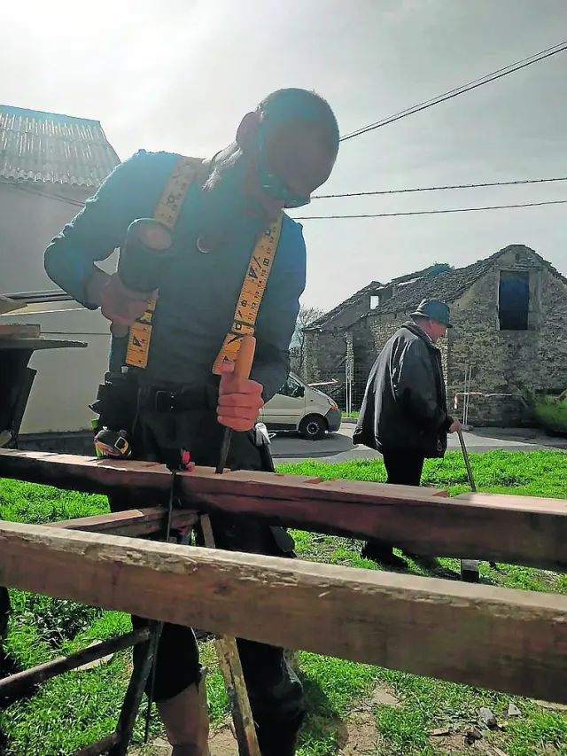 Damián Pinardi trabaja en la madera mientras un vecino de Caniás pasa por ahí.
