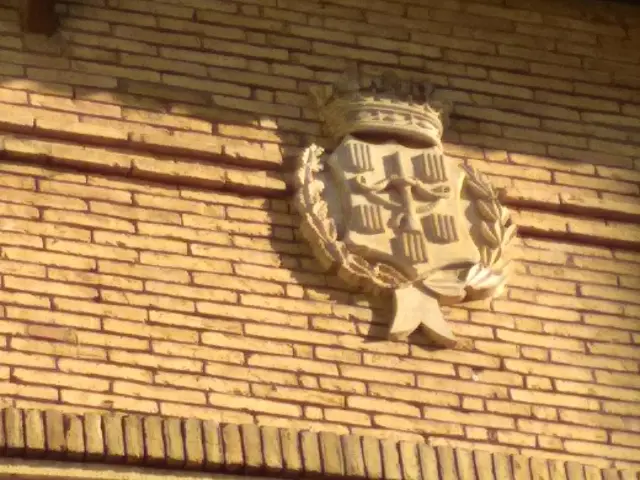 Escudo de Sariñena realizado en piedra caliza en la fachada.