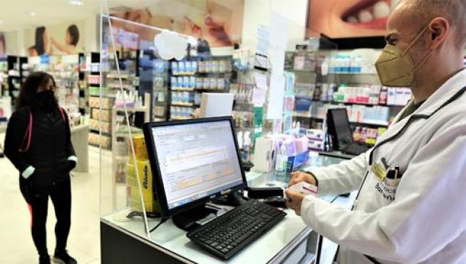 Un profesional de la farmacia Barreña, situada en la ciudad de Huesca, atiende a una clienta.