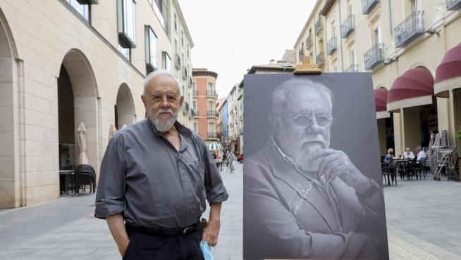 Gonzalo Suárez, posando con su retrato en los Porches de Galicia.
