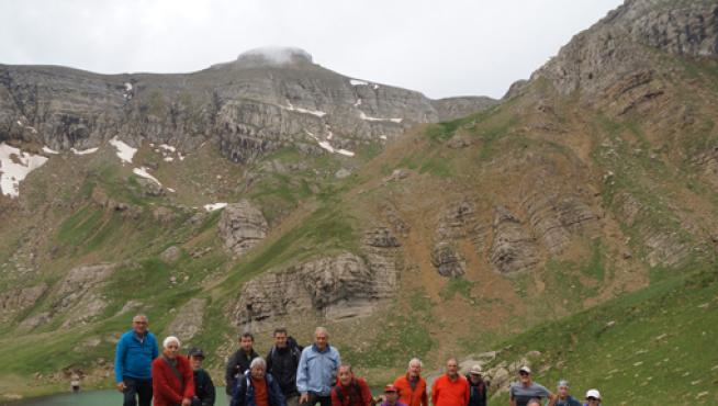 El grupo, frente al ibón y el paisaje montañoso al fondo.