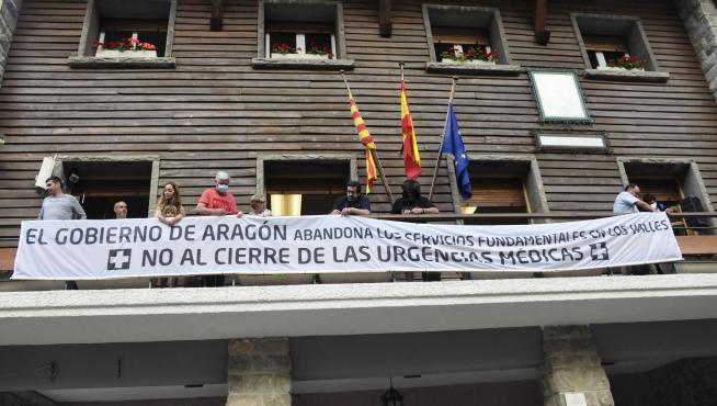 Vecinos de la zona colocando la pancarta contra el cierre de las urgencias médicas en el balcón del Ayuntamiento de Canfranc.