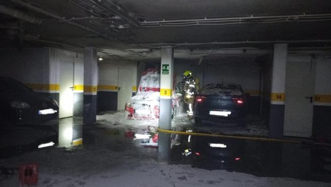 Intervención de los bomberos en el garaje de Monzón, con el vehículo calcinado.