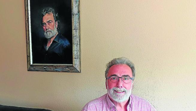 Mariano Viñuales posa junto al retrato que le hizo su amigo el pintor ‘Mabal’.