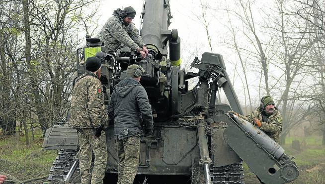 Soldados ucranianos cargan su pieza de artillería.