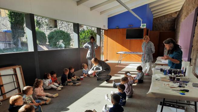Los niños de la escuela infantil participan haciendo plumas violetas en la elaboración de las alas gigantes que se colgarán esa jornada.