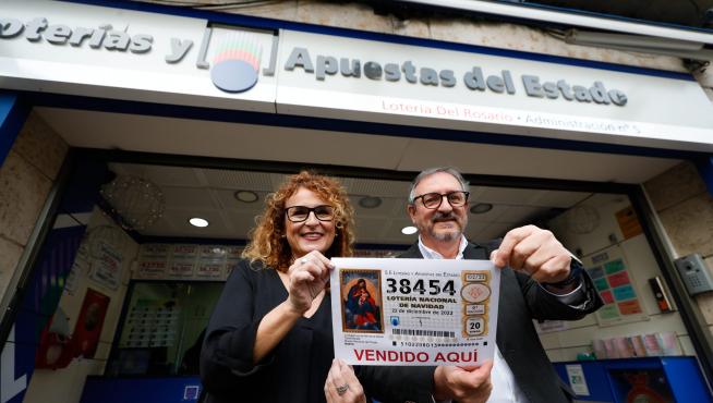 Los propietarios de la administración 'Lotería del Rosario' posan con una réplica del número 38454, uno de los quintos premios.