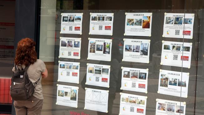 Una mujer, mirando anuncios de viviendas a la venta o en alquiler en una inmobiliaria de Huesca.