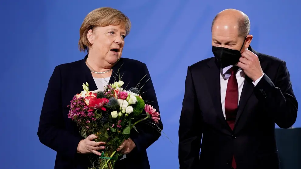 Merkel, con un ramo de flores, junto a su relevo, Olaf Scholz.