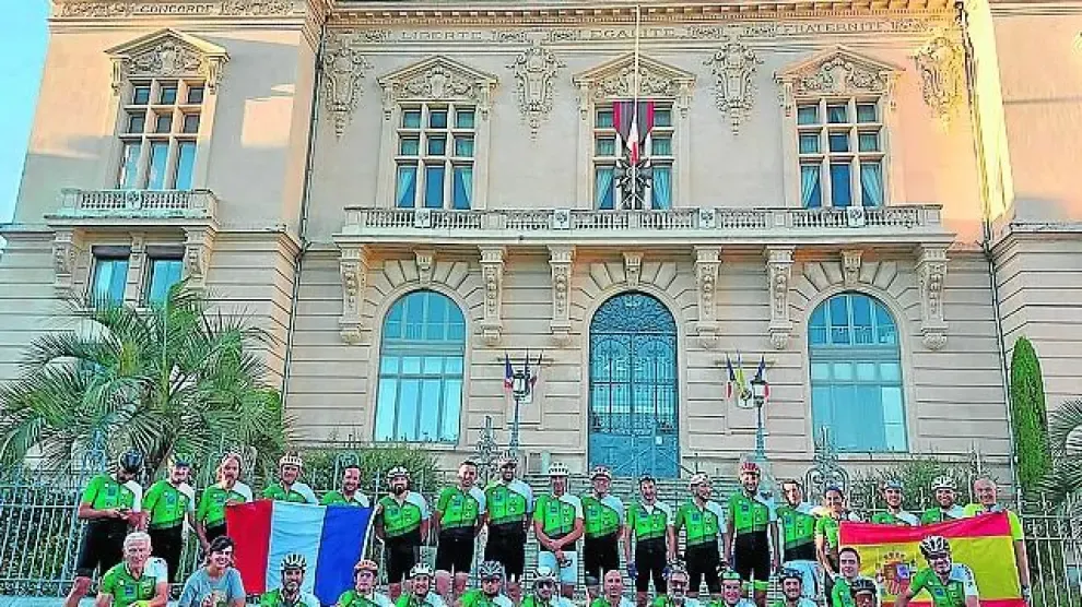 Los ciclistas oscenses posan delante del Ayuntamiento de Tarbes con la bandera francesa y la española.