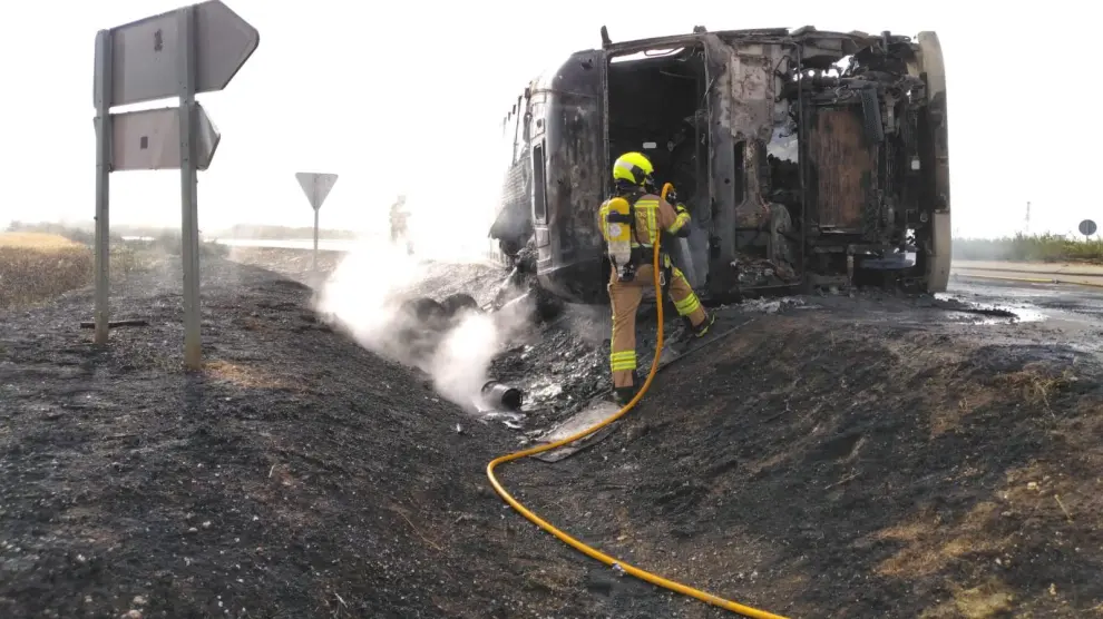 Bomberos en la extinción del camión incendiado en la carretera de Poleñino.