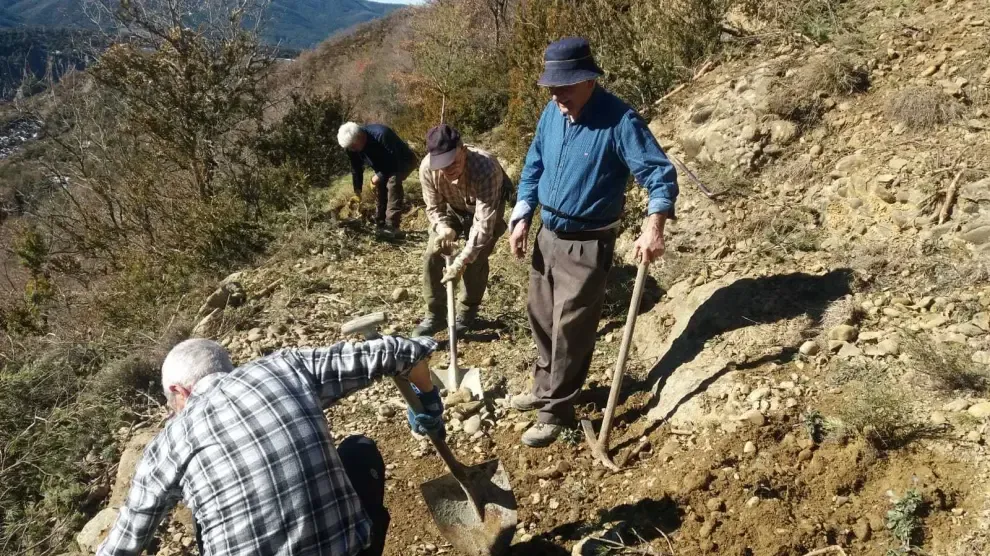 Vecinos de Yebra limpian un derrumbe de tierra en el camino de Santa Orosia