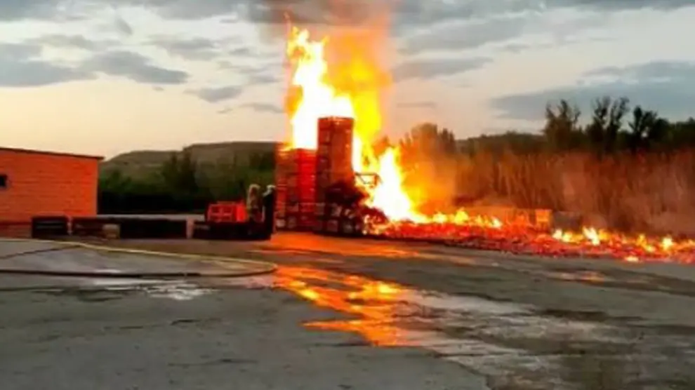El fuego quema los "palots" apilados en el exterior de un almacén de fruta en Fraga