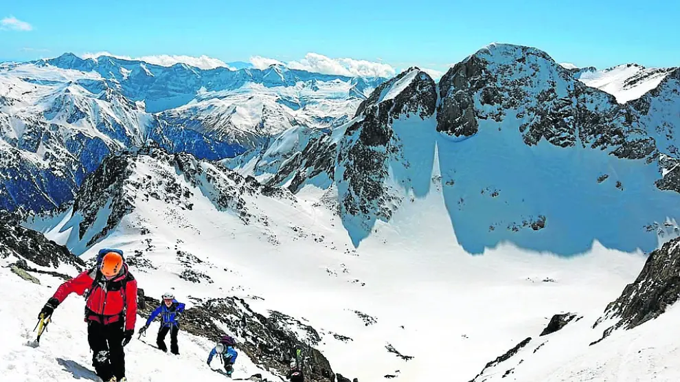 Los miembros del club de montaña ascienden las últimas pendientes antes de llegar a los picos de los Infiernos, con el Garmo Negro al fondo de la panorámica.