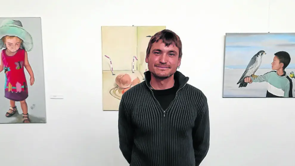 Javier Valero junto a tres de las obras que conforman la exposición Efluvios gráficos.