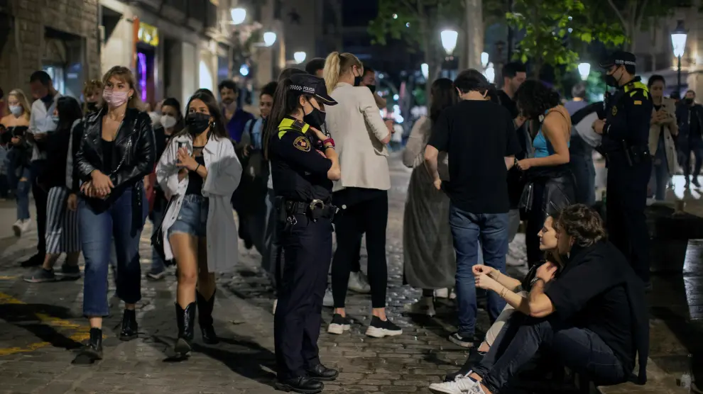 Una agente de policía pide a una pareja que se ponga la mascarilla, en la zona del Born de Barcelona, durante la noche del sábado.