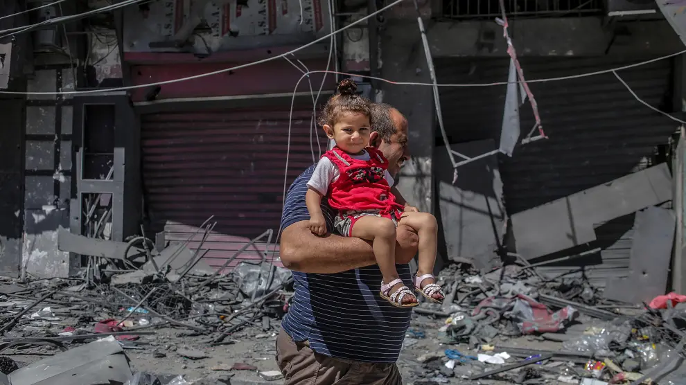Un hombre palestino huye con su hija en brazos después del ataque ayer a una torre en la ciudad de Gaza.